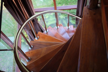 Wooden spiral stairs with rails in sun light effect.