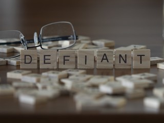 The concept of Defiant represented by wooden letter tiles - obrazy, fototapety, plakaty