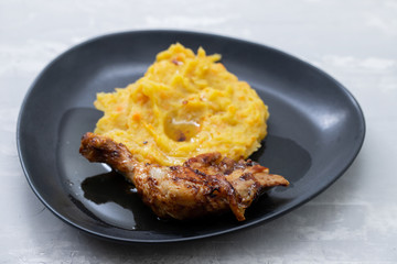 chicken with mashed sweet potato on black dish