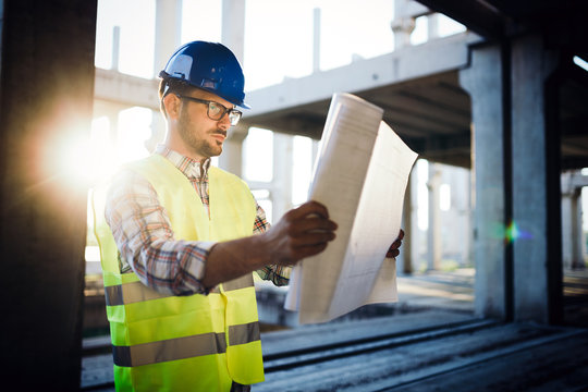 Architect holding rolled up blueprints at construction site