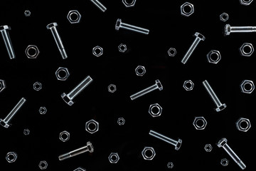 top view of scattered metal nuts and bolts pattern isolated on black