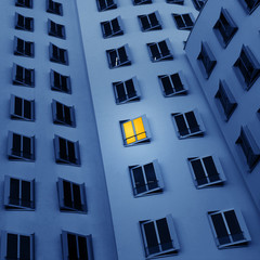 Hausfassade am Abend mit einem erleuchtetem Fenster