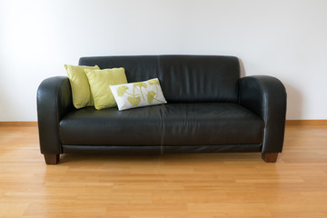 horizontal view of a dark brown leather couch with three pillows in a minimalist apartment
