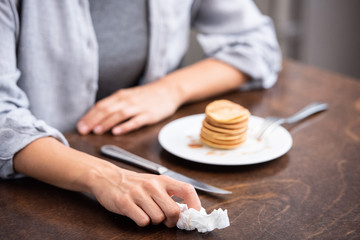 cropped view of woman holding napkin near tasty pancakes at home