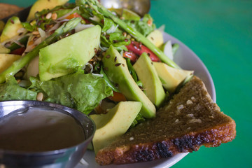 Avocado salad, garlic bread on green table. Close-up