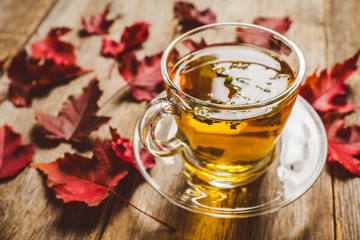 Hot tea in glass cup with atmospheric autumn decorations. Selective focus. Shallow depth of field.