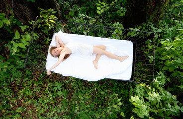 Top view of an attractive, blonde woman, stretching out in bed in the nature with free space for...