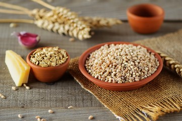 Wheat grain in dishes on the table.grains and wheat ears on a wooden table, top view