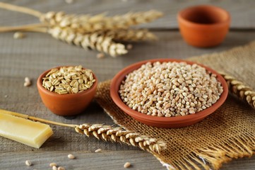 Wheat grain in dishes on the table.grains and wheat ears on a wooden table, top view