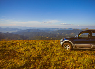 Fototapeta na wymiar Car at hill along the mountains, against blue sky