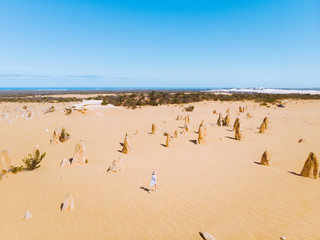 Fototapeta na wymiar Aerial drone perspective of a lone girl walking through the iconic Pinacles of Western Australia. 