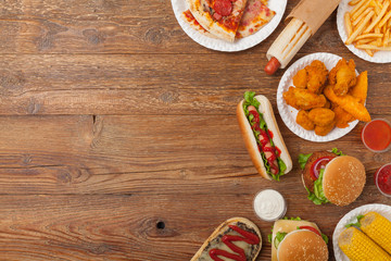 Mix of fast food, street dishes. Background with copy space. Top view. Natural wooden background.