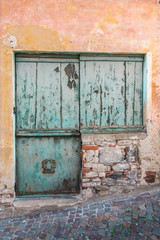 une vieille porte en bois de couleur bleu vert sur un vieux mur orange décrépi 