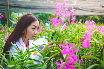 Beautiful girl, scholars and orchid research development for quality for export, use a magnifying glass to see the shape. Concept of plant research