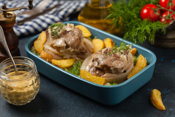 Boiled knuckle, served with cabbage and baked potatoes. Front view. Darkblue background. Dark mod.