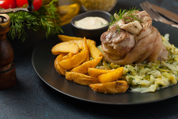 Boiled knuckle, served with cabbage and baked potatoes. Front view. Darkblue background. Dark mod.