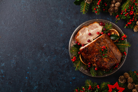 Roast pork neck in Christmas style. Dark navy blue background. Christmas accessories. Top view.
