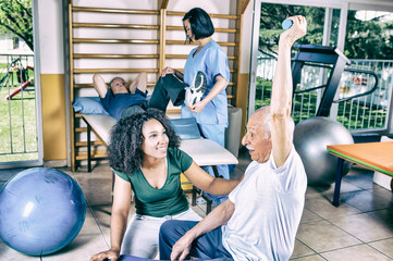 Fototapeta premium Senior retired people keeping fit in the gym with trainer
