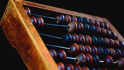 Vintage wooden abacus close up. Counting wooden knuckles. Part of the old end of the abacus on a dark background. - obrazy, fototapety, plakaty