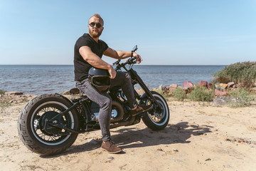 Fototapeta na wymiar Handsome bearded biker posing on his bike