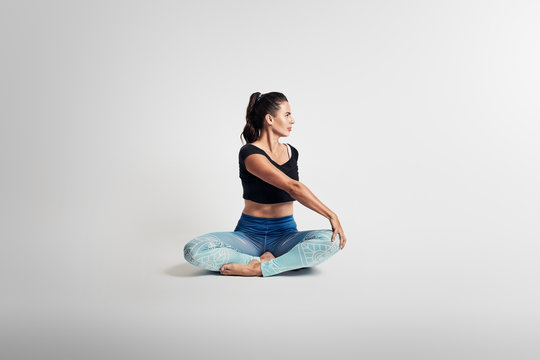 Yoga sitting pose, stretching, body in rotation, woman on white backgroung, studio photos