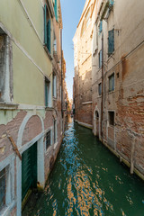 Minor side canal between two ancient buildings in Venice, Italy