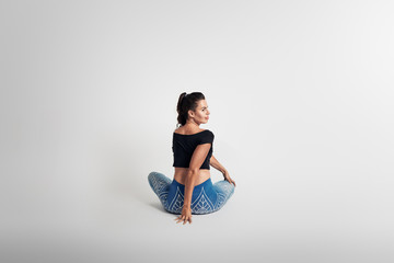 Yoga sitting pose, stretching, body in rotation from behinde, woman on white backgroung, studio...
