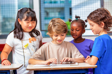 Multi ethnic elementary classroom. Four classmates enjoying school time