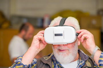 Face portrait of a elderly retired man with white beard using goggles. Virtual reality experience