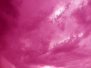 Dark stormy sky with light patch in the center. Ominous clouds. Sky clouds toned pink. Blurred sky clouds before storm.     