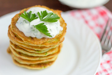 Delicious zucchini pancakes with sour cream and parsley
