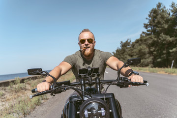 Fototapeta na wymiar Sexy bearded biker with sigar riding his motorcycle