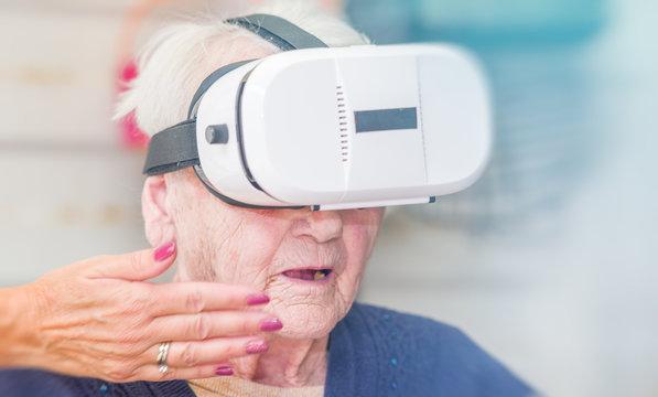 Amazed face of a elderly retired woman on the wheelchair using VR glasses. Virtual reality experience