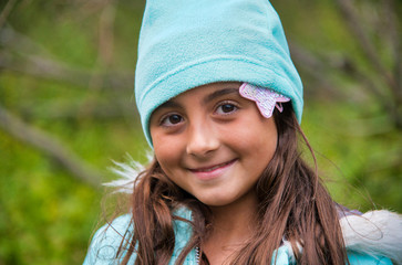 Smiling face of a young girl wearing a blue hat in the garden