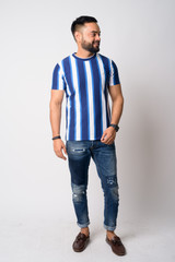 Obraz premium Full body shot of happy young bearded Indian man looking away