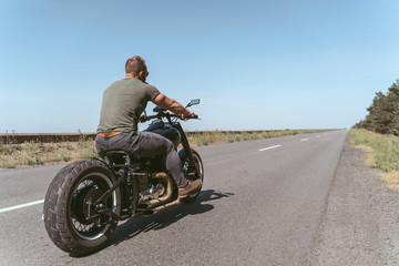Back view of a muscular confident man riding the bike