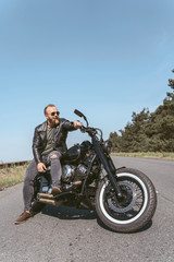 Fototapeta na wymiar Handsome bearded guy posing on his motorcycle looking to the side