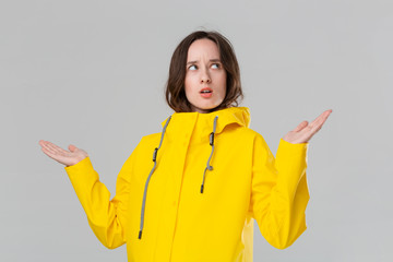 Pretty brunette girl getting dresses into yellow raincoat and checking if rain has started. Get...