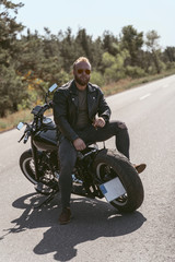 Attractive bearded biker sitting backwards on the motorcycle