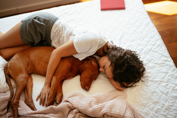 Young woman in bed with dog