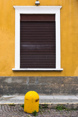une fenêtre fermée avec un mur jaune et un plot jaune en Italie