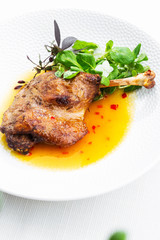 Roast duck leg with mango sauce, salade and chilli pepper on white plate, closeup. Vertical view from above, top shot. White background.