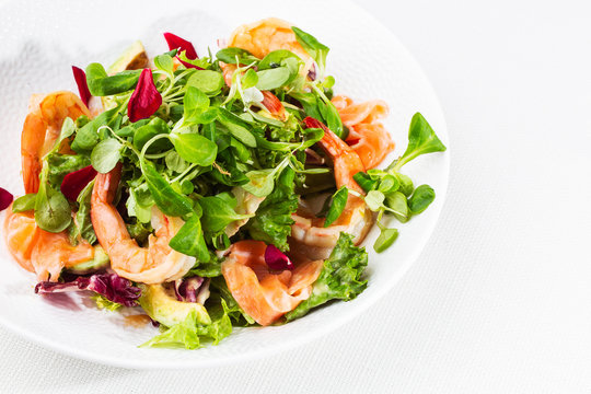 Healthy Salad. Recipe for fresh seafood. Grilled shrimps, prawns, fresh salad lettuce and avocado slices. Healthy Eating. White background. Horizontal photo.