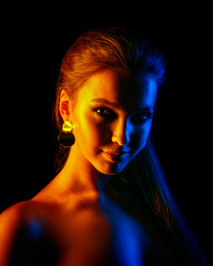 Beautiful sexy woman in colorful design and glitter vivid neon lights posing in studio. Portrait of high fashion model girl. Trendy glowing Art make-up.