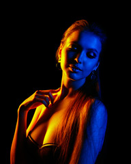 Beautiful sexy woman in colorful design and glitter vivid neon lights posing in studio. Portrait of high fashion model girl. Trendy glowing Art make-up.