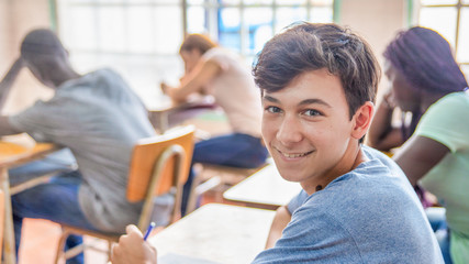 Confident caucasian teenager boy in the classroom doing school test