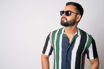 Face of young handsome bearded Indian man thinking with sunglasses