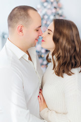 man and woman closed their eyes and hugging. Christmas tree in t