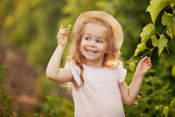 closeup portrait of happy smiling child girl in summer hat, outdoors in green park