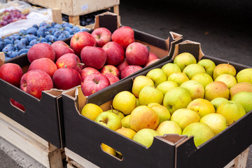 Crates of apples at a farmers market. Cardboard boxes with various kinds of apples in the local agricultural market. Fresh apples directly from the tree are sold on the open market.